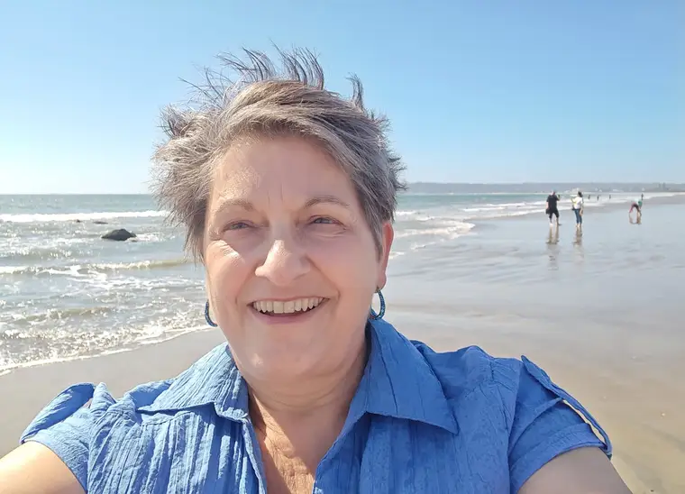 Sandy Wells smiling on the beach on a sunny day